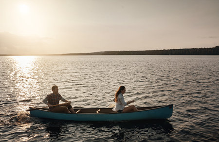 Couple, canoe and sunset on lake for adventure, holiday and outdoor weekend. Travel and man with...