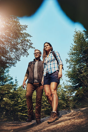 Couple, hiking and explore nature with smile, low angle and bonding with tourism on summer break....
