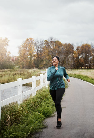Music, running and woman in nature for cardio, body wellness or endurance workout with space....