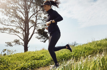 Hill, running and woman with fitness, exercise for health benefits and challenge in nature. Outdoor,...