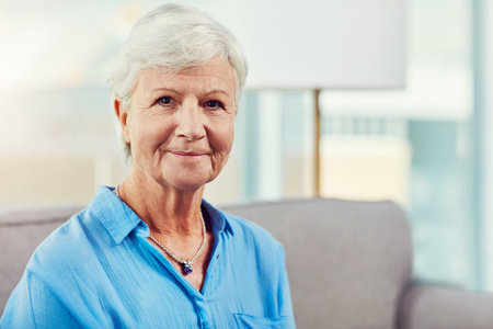 Portrait, smile and elderly woman on couch in home, relax or positive attitude for retirement...