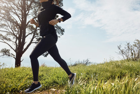 Woman, legs and running on grass with exercise, endurance training and race preparation for...