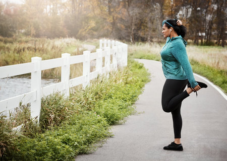 Woman, stretching and preparation with earphones in park for workout music or outdoor training....