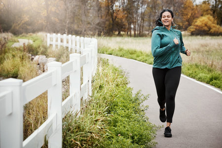 Woman, workout and running outdoor with earphones, endurance training and music playlist for...