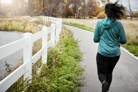 Back, woman and running outdoor with fitness, marathon preparation and cardio exercise for wellness....