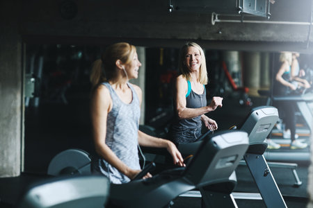 Runner, talking and fitness with women on treadmill for speed challenge, workout and training. Gym...