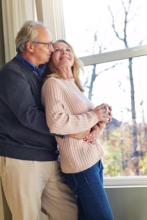 Old couple, hug and bonding with coffee, window and discussion on break, home and romance with...