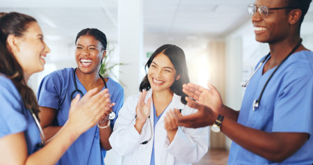 Applause, team and happy with doctors in hospital for good news, healthcare support. Medical achievement, collaboration and with group of people in clinic for celebrationの写真素材