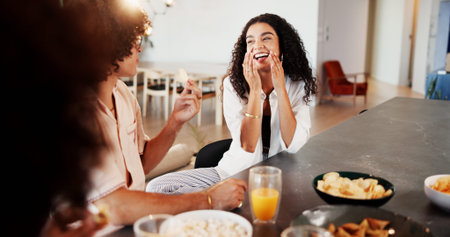 Woman, friends and laugh with lunch in home with reunion, break or chat for gossip with snacks. People, group and smile for funny conversation, memory and drinks for bonding with story at apartmentの写真素材