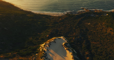 Ocean, rocks and above at beach, landscape and dunes with nature, environment and plants on hill....