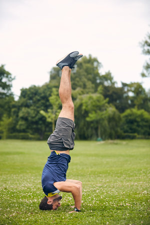 Fitness, man and headstand in park with exercise, endurance challenge and strength training for...