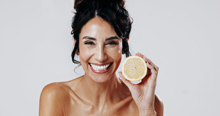 Happy woman, portrait and skincare with lemon in studio for detox on a white background. Female person, model or smile with natural organic citrus fruit for anti aging diet, vitamin C or antioxidantsの写真素材