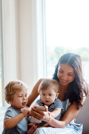 Smile, phone and mother with kids on sofa for bonding, family relationship and child development....