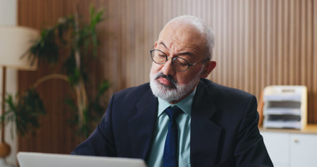 Laptop, thinking and businessman in office with insight, problem solving or funding ideas for budget pitch. Mature, financial consultant or firm with tech for online report, proposal or investmentの写真素材