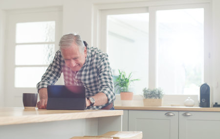 Coffee, kitchen and tablet with senior man in home for digital review or online research. App,...