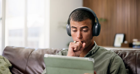 Surprise, tablet and man on sofa with headphones for online videos, subscription or watching movies....