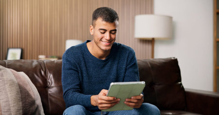 Man, tablet and smile on sofa for social media, communication or entertainment in home living room....