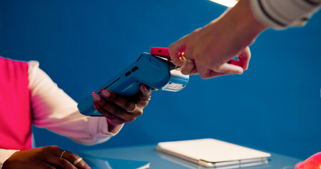 Hands, phone and pos for payment at front desk for booking, machine and fintech on blue background....