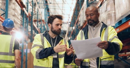 Supply chain, paper and men in warehouse, talking and planning for export, feedback and distribution. Employees, teamwork or people in factory, meeting or import schedule for logistics or inspectionの写真素材