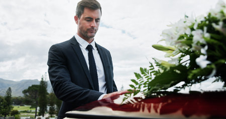 Sad, man and funeral in graveyard with coffin, grief and bereavement for burial ceremony of loved...
