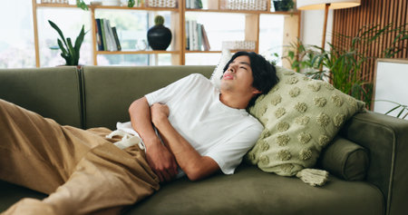 Couch, discomfort and man with stomach pain in home, indigestion or food poisoning for gastro...