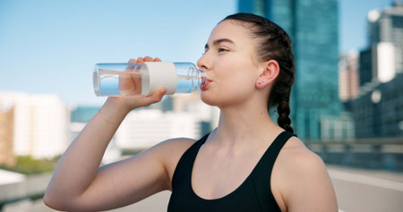 Woman, fitness or drinking with water bottle for hydration, sustainability or thirst in city....
