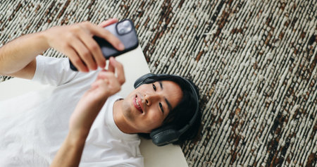 Yoga mat, music and Asian man with smartphone in home for sound, pilates playlist and top view....