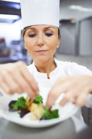 Chef, plate and hands of woman in restaurant for catering service, fine dining or prepare dish. Hospitality, presentation and female person for cooking meal, food industry or dinner in kitchenの写真素材
