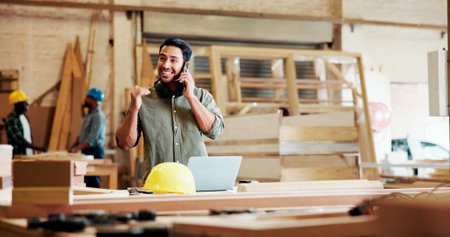 Carpenter, man and talk in factory with phone call, laptop and project discussion for manufacturing....