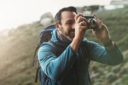 Forest, photography and happy man with camera in nature for travel, hiking or journey memory. Jungle, backpack and mature wildlife photographer with digital lens for adventure, explore or discoveryの写真素材