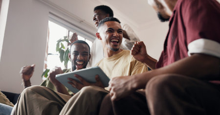 Fist pump, men and tablet for soccer results, celebration or online watch for sports update. Victory, people or friends in home, excited or tech for entertainment, winning or digital app for footballの写真素材