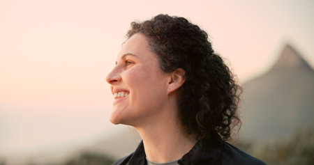 Hiking, nature and woman with smile for trekking, view and adventure with sunset. Travel, tourism and happy person on holiday or vacation for wellness, walking and exercise outdoors on mountainの写真素材