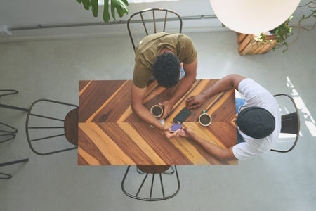 Above, people and friends with phone at cafe for social media, browsing website and reunion. Men, reading and mobile app with coffee, online message and hangout with notification update at restaurantの写真素材