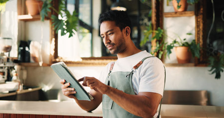 Typing, tablet and man in cafe, internet or service for online order, hospitality or startup website. Barista, entrepreneur or person in restaurant, tech for inventory or planning menu to check price