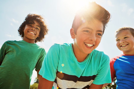 Friends, low angle and boys outdoor with smile, peer support and bonding together on summer holiday. Flare, happy and children with positive growth, companion or social development in spring vacation