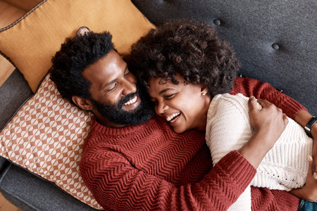 Laugh, love and happy couple hug in home with relationship support, connection security and care. African man, woman and cuddle on sofa with partner loyalty, funny joke or relax together from above