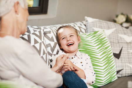 Relax, laughing and old woman with child on sofa in home for bonding, support and love. Retirement, connection and funny joke with grandmother and granddaughter in family house for weekend break