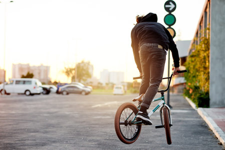 City, back and man on bicycle for cycling, training skill or tricks in urban town to practice. Cool trick, athlete or stunt biker in parking lot for exercise, fitness or outdoor sports for biking