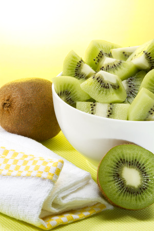 Fresh and healthy kiwis bowl with a yellow prop and sunny backgroundの写真素材