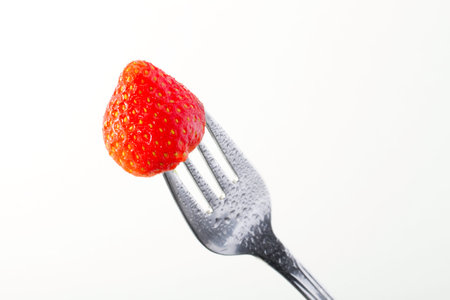 fresh strawberry in a fork isolated on a white background