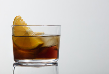 classic glass of red vermouth with ice and orange slice on a white background with a beautiful reflectionの写真素材