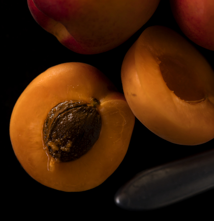 opened apricot on a black stone kitchen table with an old knifeの写真素材