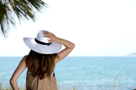 young girl looking the horizon with a white straw hat