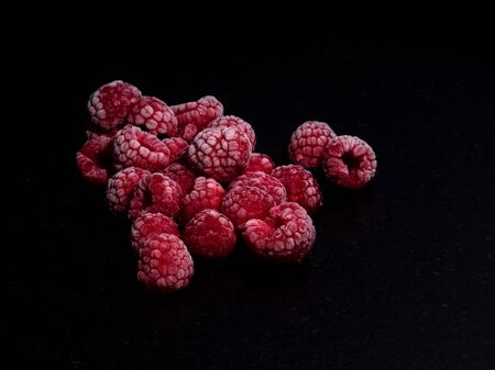 raspberries frozen on a black stone tableの写真素材