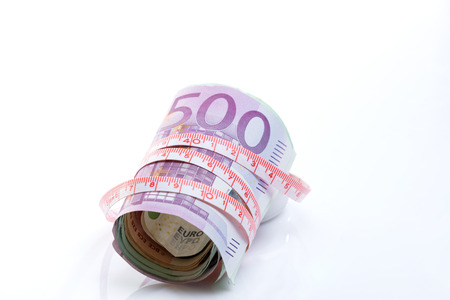 roll of euros fit with a meter tape around them on a white backgroundの写真素材