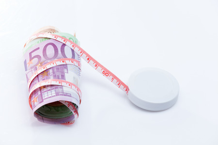 roll of euros fit with a meter tape around them on a white backgroundの写真素材