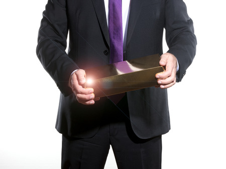 successful businessman showing a big gold ingotの写真素材