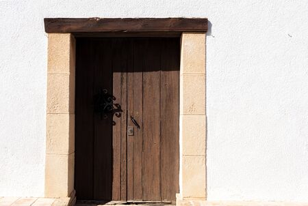 old wooden door in a white wall with light brown stones around. Mediterranean coast, Spain, Morairaの写真素材