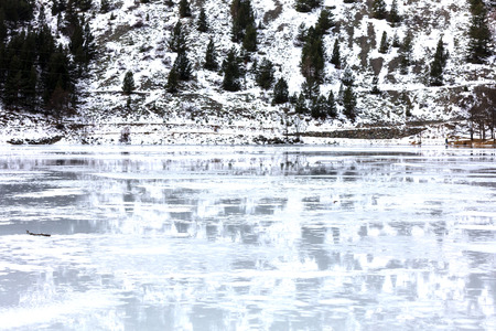frozen lake reflecting the snowy mountain landscapeの写真素材