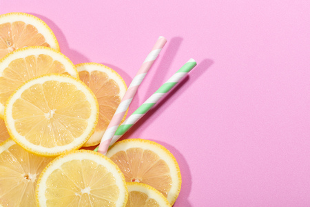 slices of lemon on pink colored background, with two stripped strawsの写真素材